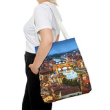 Person holding a tote bag with a scenic city design on a white background