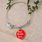 Silver bracelet with a red charm that says 'Best Nonna Ever' on a beige background.