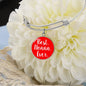 Silver bracelet with a red charm reading 'Best Nonna Ever' on a white flower background