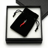Black velvet drawstring bag with a red item inside, placed on white tissue paper in a black box.