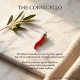 Red cornicello pendant with olive branch on marble surface, text about Cornicello's symbolism.