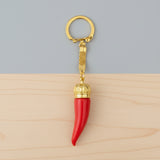 Red keychain with gold crown and gold ring on a white background