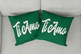 Two green pillows with 'Ti Amo' text on a light gray couch.