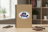 Brown notebook with 'ITALIA' sticker on a wooden surface with pens and a coaster.